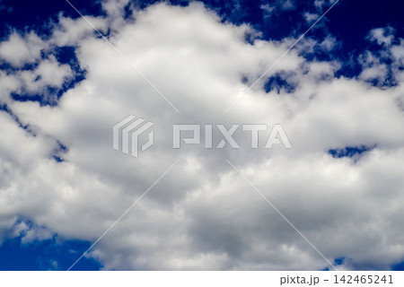 a large fluffy white cumulus cloud against a deep blue sky on a bright sunny day 142465241