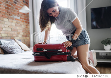 Happy Woman Packing Suitcase In Room For Upcoming Travel Preparing For A Holiday Journey 142465350