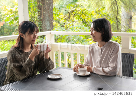 木立のカフェで談笑する女性二人 木立のカフェで談笑する女性二人 142465635