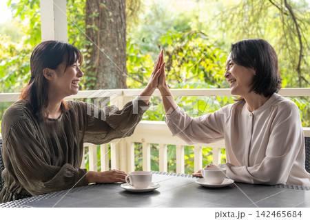 木立のカフェでハイタッチで盛り上がる女友達　親子　相談 142465684