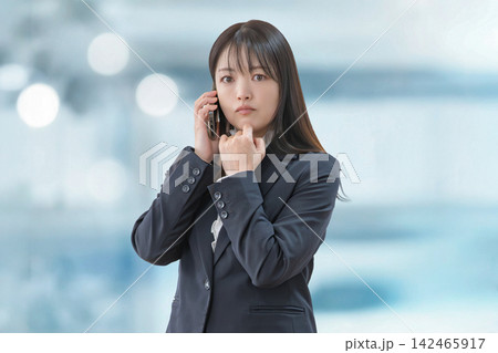 電話で真剣な表情のスーツ姿の女性 電話で真剣な表情のスーツ姿の女性 142465917