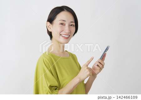 スマホを持つミドル女性　白背景　ポートレート　カメラ目線 142466109