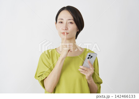 スマホを持って内緒のポーズをするミドル女性　白背景 142466133