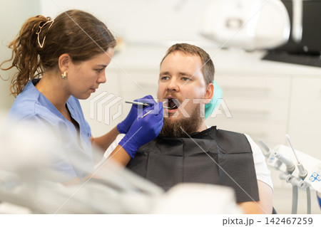 man sits in a chair at an appointment at a dental clinic man sits in a chair at an appointment at a dental clinic 142467259