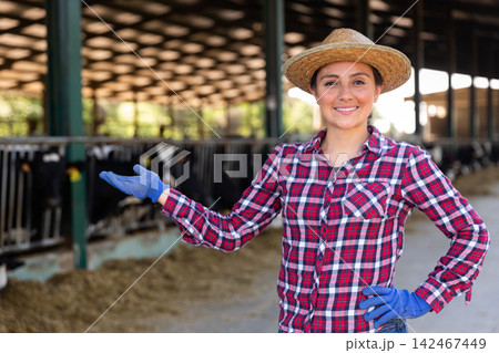 Female farmer engaged in breeding of cows posing in cowshed 142467449