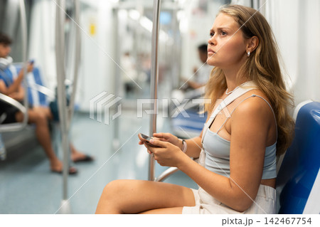 Young girl sitting in wagon holding mobile phone in hand 142467754