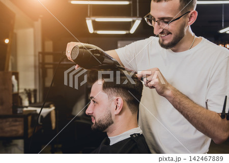 Young man with trendy haircut at barber shop. Barber does the hairstyle and beard trim. Young man with trendy haircut at barber shop. Barber does the hairstyle and beard trim. 142467889