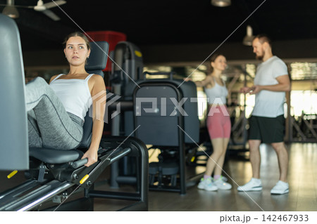 Young woman training her leg muscles on machine Young woman training her leg muscles on machine 142467933