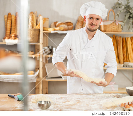 Guy works in bakery as baker, kneads dough, works with flour. Guy works in bakery as baker, kneads dough, works with flour. 142468159