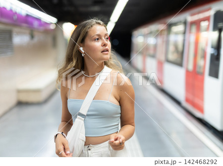 Young woman with headphones standing at metro station Young woman with headphones standing at metro station 142468292