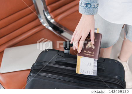 Close up hands woman tourist going to flight with suitcase holding Thailand passport and airline ticket on baggage 142469120
