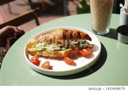 Enjoying a croissant with vegetables and tea Enjoying a croissant with vegetables and tea 142469674