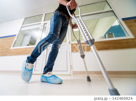 Injured man trying to walk on crutches in the hospital. Injured man trying to walk on crutches in the hospital. 142469924