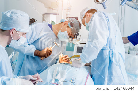 Spinal surgery. Group of surgeons in operating room with surgery equipment. Laminectomy 142469944