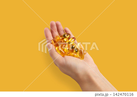 Omega 3. Hand displays softgel capsules of omega fish oil in vibrant setting. Omega 3. Hand displays softgel capsules of omega fish oil in vibrant setting. 142470116