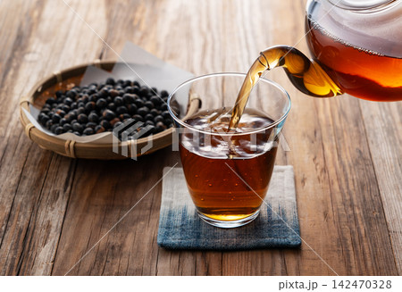 コースターに乗ったグラスにガラスポットから注がれる黒豆茶 シズル感と和風健康茶 コースターに乗ったグラスにガラスポットから注がれる黒豆茶 シズル感と和風健康茶 142470328