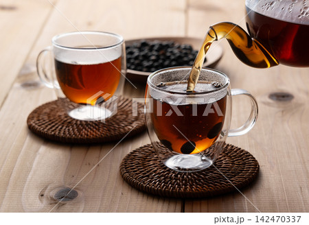 ガラスポットからダブルウォールグラスに注がれる温かい黒豆茶 シズル感とカフェ風のティータイム ガラスポットからダブルウォールグラスに注がれる温かい黒豆茶 シズル感とカフェ風のティータイム 142470337