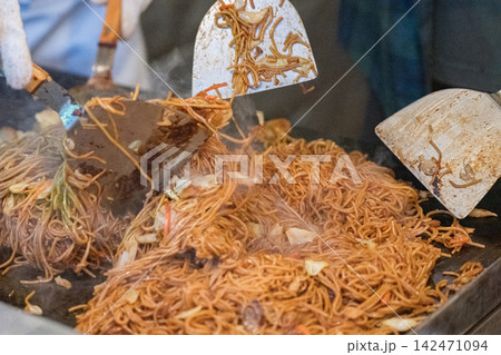三本のヘラで麺を豪快に返す屋台の一場面 142471094