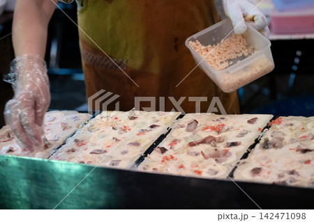 屋台の鉄板で焼く海鮮入り生地にトッピングする様子 屋台の鉄板で焼く海鮮入り生地にトッピングする様子 142471098
