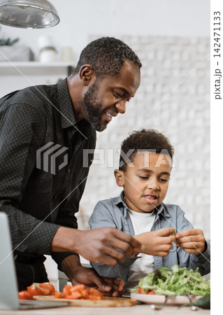 A father and his young son are happily preparing a salad together in a bright kitchen, learning to cook A father and his young son are happily preparing a salad together in a bright kitchen, learning to cook 142471133
