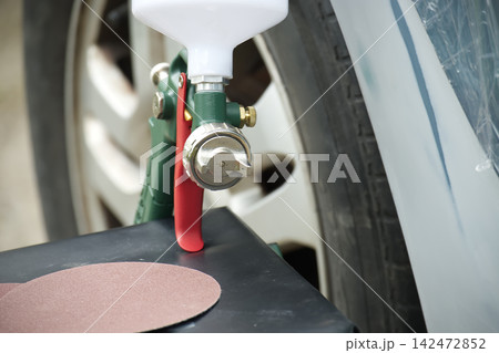 Paint Spray Gun Resting on a Workshop Workbench Near an Auto Body Repairing Station Paint Spray Gun Resting on a Workshop Workbench Near an Auto Body Repairing Station 142472852