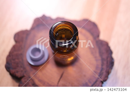 Amber Glass Bottle with Open Cap on Wooden Slice Amber Glass Bottle with Open Cap on Wooden Slice 142473104