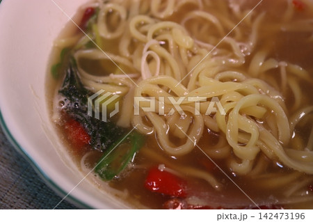 Steaming Bowl of Noodle Soup with Broth and Vegetables Steaming Bowl of Noodle Soup with Broth and Vegetables 142473196