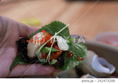 Hand Holding Artisanal Seafood Dish with Garnishes Hand Holding Artisanal Seafood Dish with Garnishes 142473206