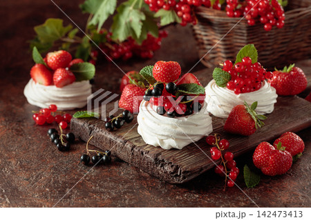 Pavlova dessert with fresh berries and mint on an brown vintage table. Pavlova dessert with fresh berries and mint on an brown vintage table. 142473413