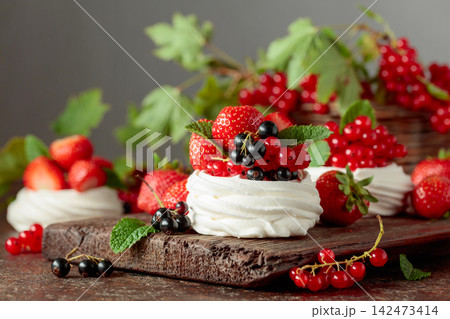 Pavlova dessert with fresh berries and mint on an brown vintage table. Pavlova dessert with fresh berries and mint on an brown vintage table. 142473414