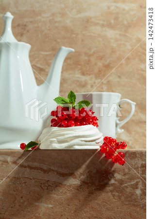 Pavlova dessert with red currant, and mint on a beige table. Pavlova dessert with red currant, and mint on a beige table. 142473418
