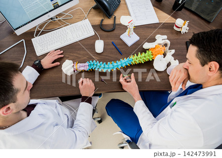 Doctor show polyaxial screw on the spine model. Spine fixation systems Doctor show polyaxial screw on the spine model. Spine fixation systems 142473991
