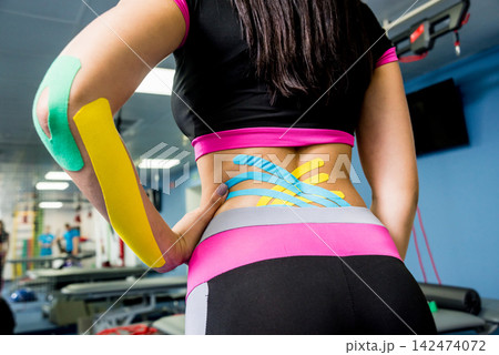 Kinesiotaping. Physical therapist applying tape to young beautiful womans spine, hand and cubit. Kinesiotaping. Physical therapist applying tape to young beautiful womans spine, hand and cubit. 142474072