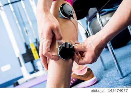 Physical therapist install electrostimulator on the muscles of the legs. Fitness training with an electrostimulator. Physical therapist install electrostimulator on the muscles of the legs. Fitness training with an electrostimulator. 142474077