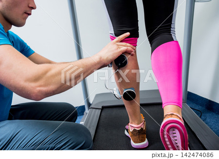 Physical therapist install electrostimulator on the muscles of the legs. Fitness training with an electrostimulator. Physical therapist install electrostimulator on the muscles of the legs. Fitness training with an electrostimulator. 142474086