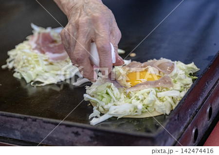 豚肉と卵をのせるお好み焼き作りの様子 142474416