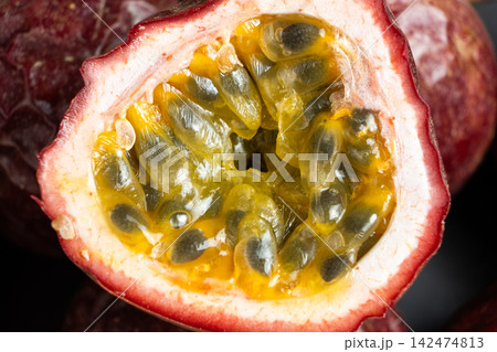 Close up of fresh halved passion fruit revealing juicy yellow seeds. Close up of fresh halved passion fruit revealing juicy yellow seeds. 142474813