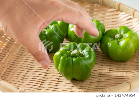 ザルにのせた伝統野菜のかぐら南蛮に手を伸ばす男性（9月） 142474954