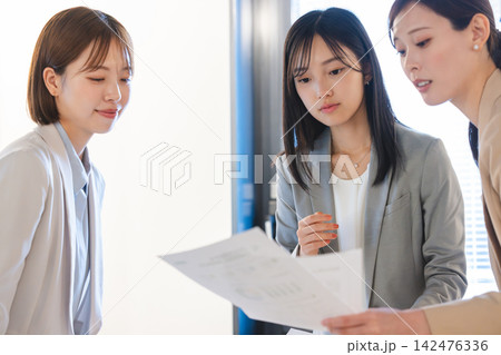 資料を見て打ち合わせをする女性ビジネスパーソン 142476336