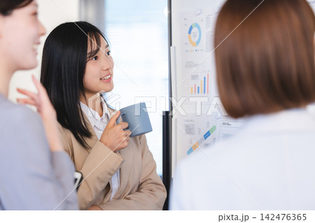 ホワイトボードの資料を見つめ真剣に意見を出し合う女性ビジネスパーソンたち ホワイトボードの資料を見つめ真剣に意見を出し合う女性ビジネスパーソンたち 142476365