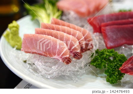 Elegant Presentation of Fresh Red Tuna Sashimi Slices on White Decorative Strands Elegant Presentation of Fresh Red Tuna Sashimi Slices on White Decorative Strands 142476493