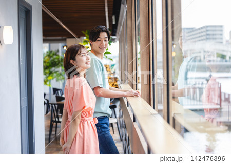 景色を眺めながら穏やかに話す男女 景色を眺めながら穏やかに話す男女 142476896