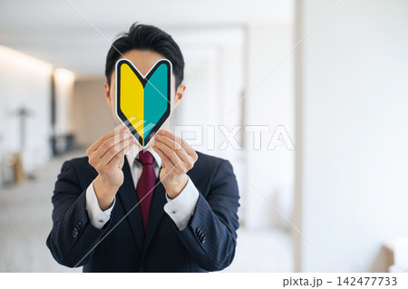 初心者マークを持つ男性。免許、新入社員、ビギナー、資格、スキル、勉強、学習、研修、試験、合格、就活 142477733