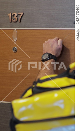 Vertical video. A food delivery person in a yellow uniform. Delivering coffee and food to a person's home. Inside shot. Food delivery concept. 142478466
