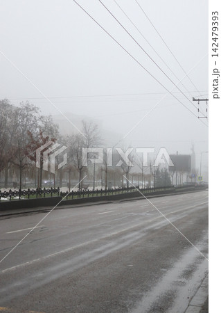 Fog covers a busy street with parked cars and moving vehicles. Fog covers a busy street with parked cars and moving vehicles. 142479393