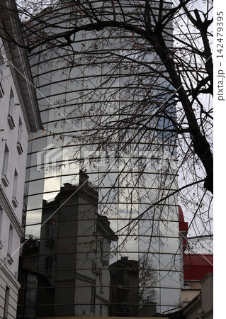 Building reflects in glass structure on a cloudy day with bare trees nearby. Building reflects in glass structure on a cloudy day with bare trees nearby. 142479395