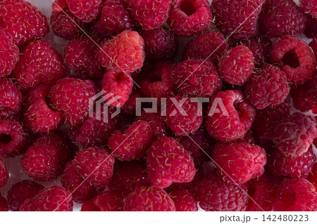 Fresh ripe raspberries filling the frame in a close-up top view. Red summer berries with natural texture and visible drupelets for food, nutrition and healthy eating concepts Fresh ripe raspberries filling the frame in a close-up top view. Red summer berries with natural texture and visible drupelets for food, nutrition and healthy eating concepts 142480223