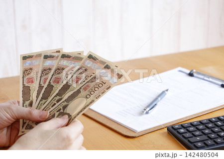 紙幣を持つ人の手元 お金の管理や支払いのイメージ素材 紙幣を持つ人の手元 お金の管理や支払いのイメージ素材 142480504