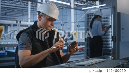 Engineer Working at Computer with Colleagues at Server Rack in Smart Factory Engineer Working at Computer with Colleagues at Server Rack in Smart Factory 142480960