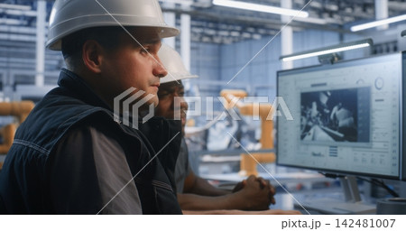 Engineers Controlling Automated Robotic Assembly from Glass Office 142481007